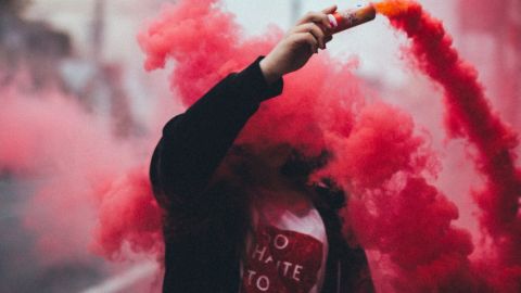 Comment les start-up crée une économie parallèle illégale Un homme dans un sweat noir en train de propager un fumigène rouge
