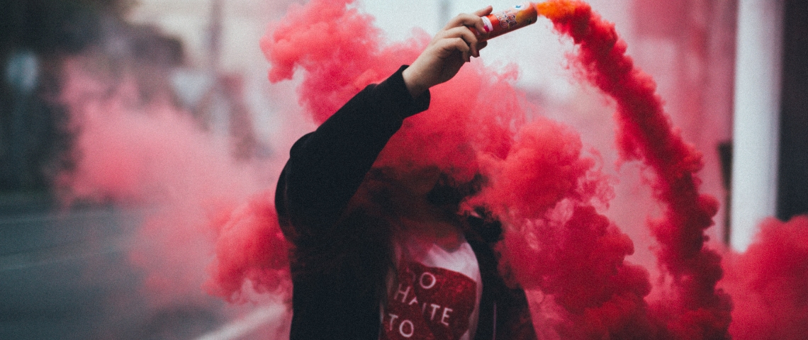 Comment les start-up crée une économie parallèle illégale Un homme dans un sweat noir en train de propager un fumigène rouge