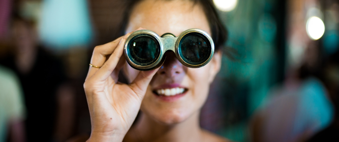 Quels KPIs surveiller pour quels objectifs ? Une femme qui regarde à travers des jumelles