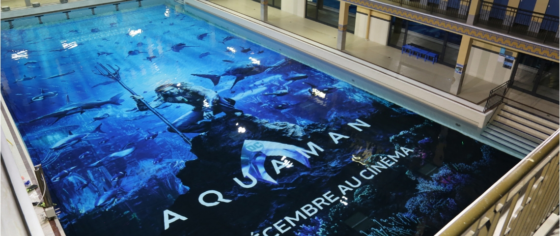Aquaman à la piscine Pailleron La piscine Pailleron avec l'affiche d'Aquaman au fond