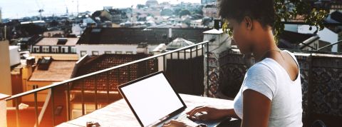 Boom du freelancing : à qui profite la tendance ? une femme noire tape sur son ordinateur sur un balcon