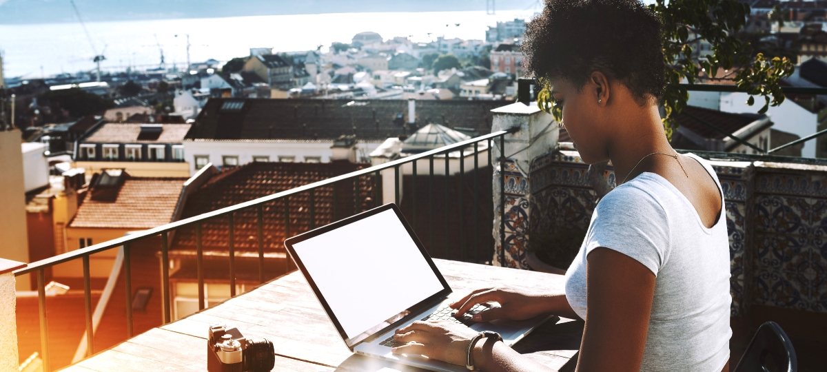 Boom du freelancing : à qui profite la tendance ? une femme noire tape sur son ordinateur sur un balcon