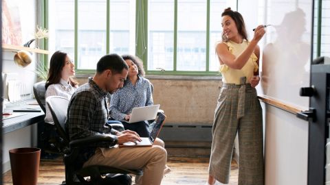 une femme forme ses collègues en petit groupe