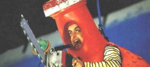 un homme dans un costume orangina rouge tient une tronçonneuse