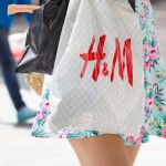 Une jeune femme en robe portant un sac H&M dans la rue