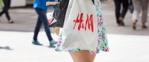 Une jeune femme en robe portant un sac H&M dans la rue