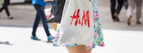 Le nouveau patron de H&M veut faire moins de promos Une jeune femme en robe portant un sac H&M dans la rue