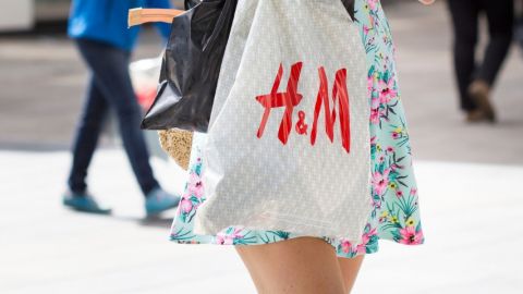 Une jeune femme en robe portant un sac H&M dans la rue
