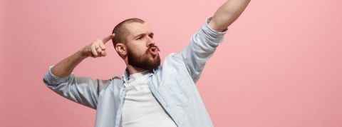 Comment être plus productif au bureau ? Un homme en train de faire une power pose sur un fond rose
