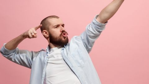 Un homme en train de faire une power pose sur un fond rose