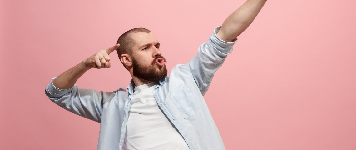 Comment être plus productif au bureau ? Un homme en train de faire une power pose sur un fond rose