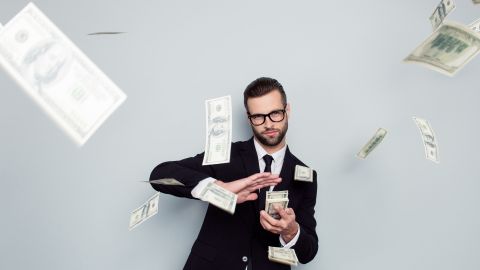 un homme en costume jette des billets de banque