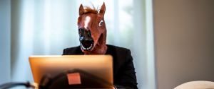 Un homme au masque de cheval devant son ordinateur