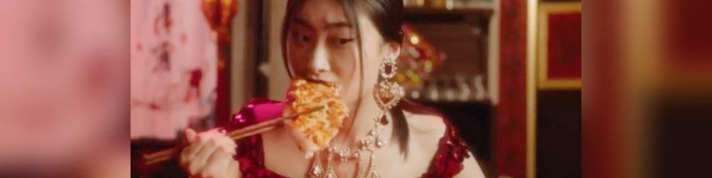 Une femme chinoise en train de manger une pizza avec des baguettes