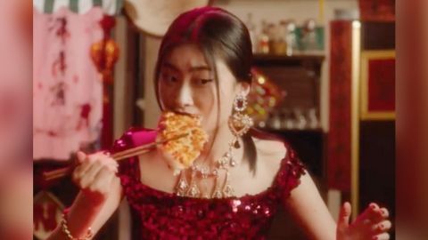 Une femme chinoise en train de manger une pizza avec des baguettes