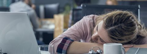 une jeune femme assoupie au travail