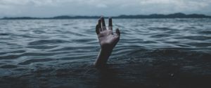 une main essaie de sortir de l'eau, un homme se noie