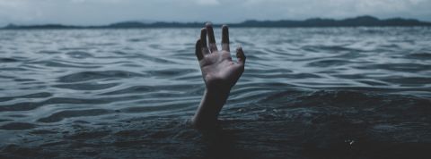 une main essaie de sortir de l'eau, un homme se noie