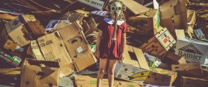 Une petite fille avec un masque à gaz devant un amoncellement de cartons
