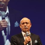 Jeremy Rifkin en train de parler au micro avec un écran géant en arrière plan