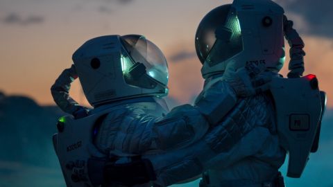 Deux personnes en combinaison d'astronaute qui se font un câlin