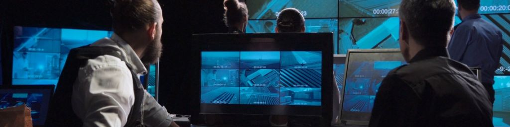 Des hommes dans une piece sombre qui regardent des écrans
