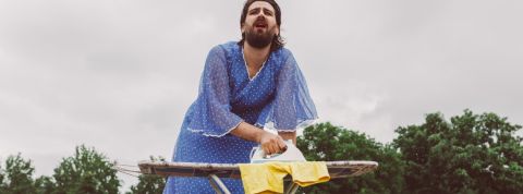 Un homme travesti repasse ses vêtements