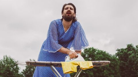 Un homme travesti repasse ses vêtements