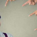 Un homme en train de se faire pointer du doigt par quatre mains de femmes