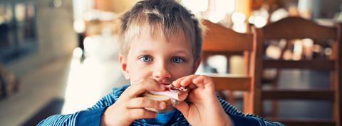 un jeune garçon mange un sandwich au jambon