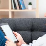 homme allongé dans un canapé avec un casque et une liseuse