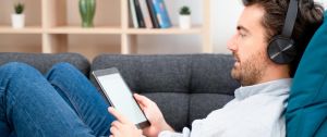 homme allongé dans un canapé avec un casque et une liseuse