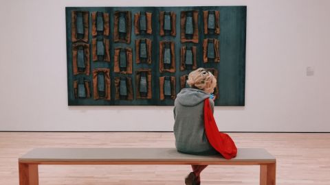 une jeune femme au musée assise devant un tableau