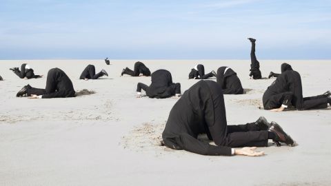hommes la tête dans le sable