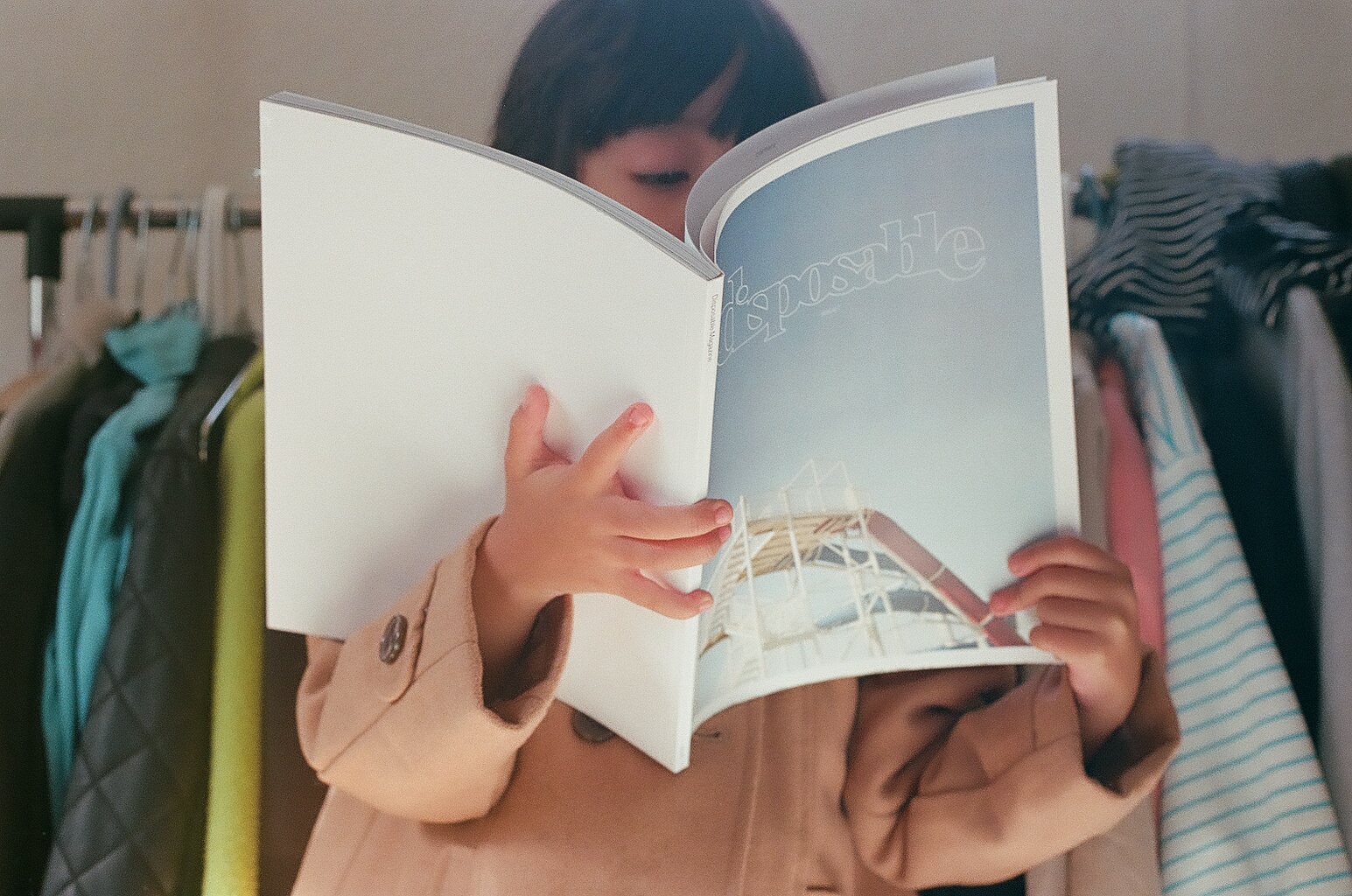 une fille lisant, cachée, par un magazine