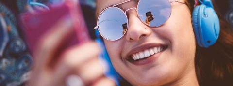 Une jeune femme à lunettes écoute son téléphone avec un casque