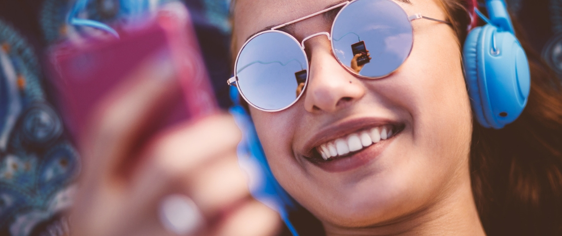 Une jeune femme à lunettes écoute son téléphone avec un casque