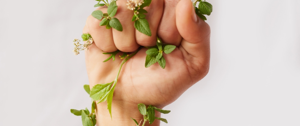 Top 5 des métiers engagés qui recrutent Le poing d'une femme, serré, entouré de feuilles
