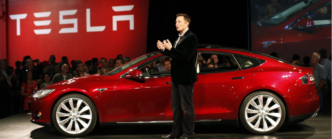 Elon Musk rend les brevet de Tesla public Elon musk devant une Tesla rouge