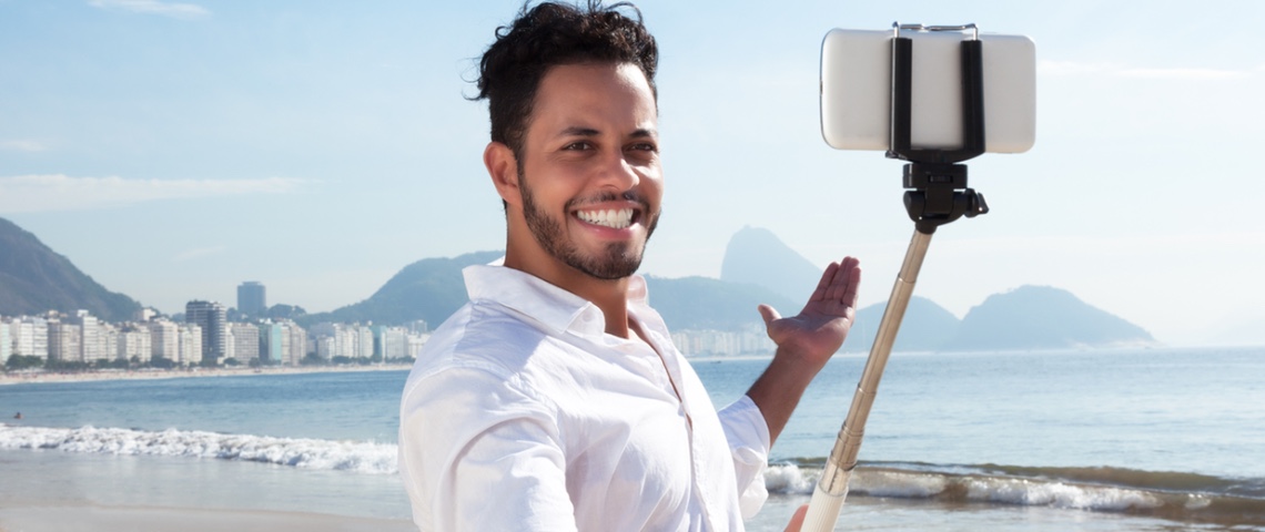 Pires technos du 21ème siècle Jeune homme à la plage, se prenant en photo avec une perche à Selfie