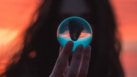 une femme tient une boule de cristal devant son visage