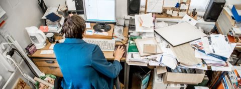 Une étude s'intéresse à la façon dont les Français rangent leur bureau Un homme de dos, assis à son bureau mal rangé