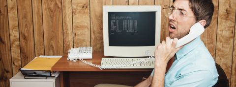 Peut-on éviter les burn-out ? Un homme interloqué au téléphone, derrière un ordinateur rétro