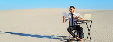 Pourquoi faut-il revaloriser les commerciaux en agence ? Un homme, seul, assis à un bureau dans le désert