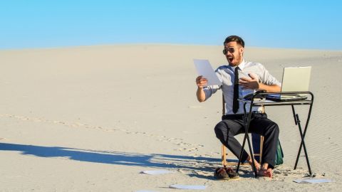 Un homme, seul, assis à un bureau dans le désert