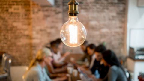 Une ampoule sur fond flouté de personnes qui travaillent sur un bureau