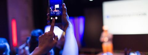 Quelles tendances pour l'événementiel 2019 ? Une personne en train de photographier une prise de parole scénique avec son téléphone portable