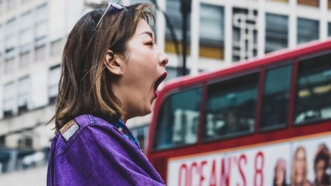 Comment la sophrologie peut aider les gens qui stressent Une femme en train de bailler devant un bus