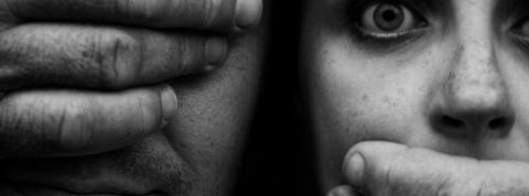 Un homme aux yeux bandés ferme la bouche d'une jeune femme