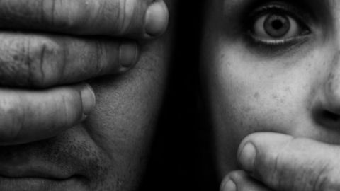 Un homme aux yeux bandés ferme la bouche d'une jeune femme